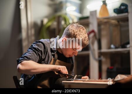 Ein junger Meister in der manuellen Herstellung von Schuhen in Seine Werkstatt arbeitet an der Herstellung von Schuhen Stockfoto