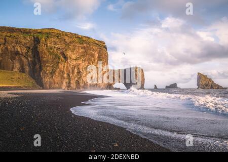 Am späten Nachmittag Blick auf die Meeresstapel und den Meeresbogen in Dyrholaey im Süden Islands. Stockfoto