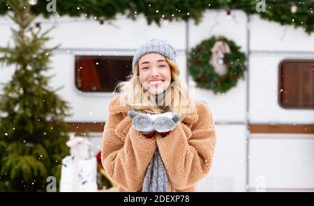 Erster Schnee. Glückliche junge blonde Frau genießen Schneefall auf Wintercampingplatz Stockfoto