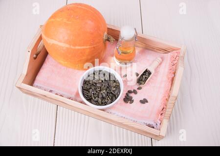 Gesundes Kürbisöl mit Kürbiskernen auf einem Holztablett Stockfoto