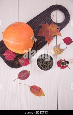 Draufsicht auf Kürbisöl, Kürbisfrüchte auf einem Holzschneidebret und Samen. Stockfoto