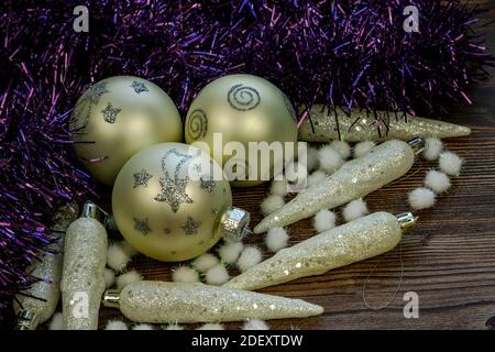 Silberne weiße Weihnachtskugeln mit Eiszapfen und dekorativem kleinen Schnee Bälle auf dem Tisch in dunklem Holzhintergrund Stockfoto