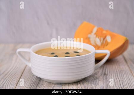 Nahaufnahme auf einem Teller mit Kürbispüree-Suppe und einem Stück Kürbis in Scheiben. Stockfoto