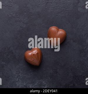 Schokoladenbonbons in Herzform auf schwarzem Stein Hintergrund Valentinstag Grußkarte Platz Draufsicht Stockfoto