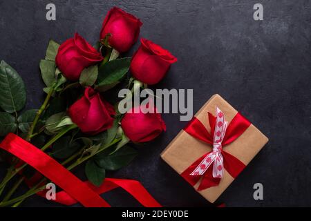 Rote Rosenblüten Bouquet und Geschenkbox auf schwarzem Stein Hintergrund Valentinstag Grußkarte Copy space Flat Lay Stockfoto