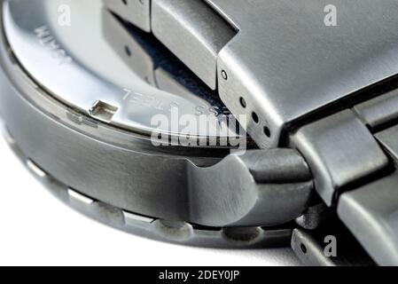 Eine Makroaufnahme eines dunklen Metalluhrgehäuses und eines Uhrenarmbands aus Edelstahl, isoliert auf weißem Hintergrund. Stockfoto