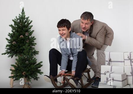 Weihnachten thematisierte horizontale Business-Paar Porträt gekleidet smart casual in blau, weiß, beige Hosen und Blazer auf grauem Hintergrund. In der Vorgruppe Stockfoto