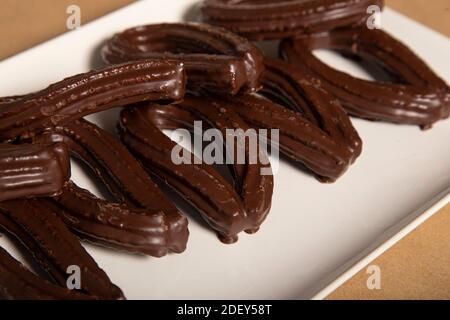 Spanische traditionelle gebraten - Teig Backwaren Churros in Schokolade Glasur Stockfoto