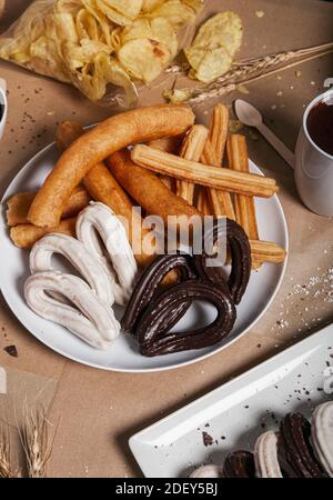 Zum Frühstück werden verschiedene typische Churros am Tisch serviert. Vertikales Bild Stockfoto