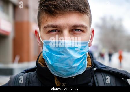 Junger Mann in der Grippemaske auf der Stadtstraße Nahaufnahme im Hochformat Stockfoto