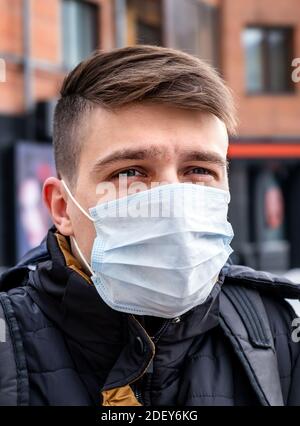 Junger Mann in der Grippemaske auf der Stadtstraße Nahaufnahme im Hochformat Stockfoto