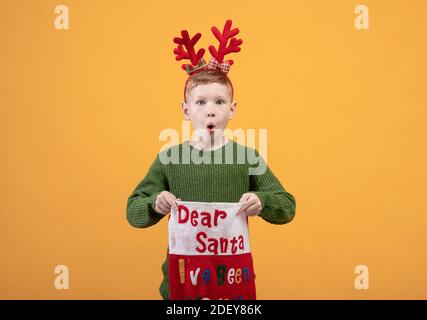 Geschockt Ingwer Junge in Rentier Kostüm halten Geschenk Socke Stockfoto