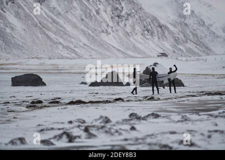 Arktische Surfer gehen nach dem Surfen am Strand vorbei Stockfoto