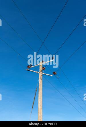 Hölzerne Telegrafenmasten mit Drähten und Isolatoren gegen eine klare Blauer Himmel Hintergrund Stockfoto