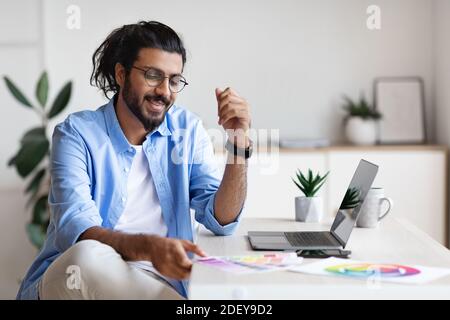 Indian Graphic Designer Arbeitet Mit Farbfeldern Und Laptop Bei Heimbüro Stockfoto