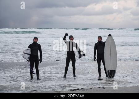 Arktische Surfer gehen nach dem Surfen am Strand vorbei Stockfoto