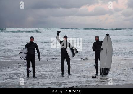 Arktische Surfer gehen nach dem Surfen am Strand vorbei Stockfoto