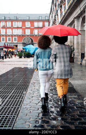 Stock Foto von zwei Mädchen zu Fuß in der Stadt und mit einem Regenschirm. Stockfoto