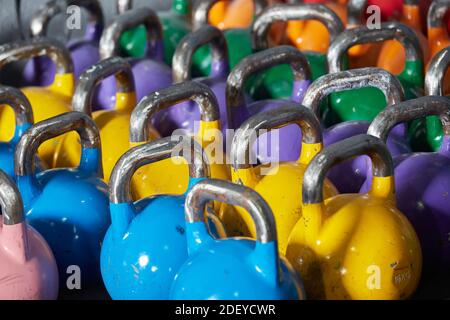 Stock Foto von einem Haufen von bunten Hanteln aus der Nähe. Sie sind aufgereiht. Es gibt blaue, gelbe, violette, grüne, orange und rote. Stockfoto