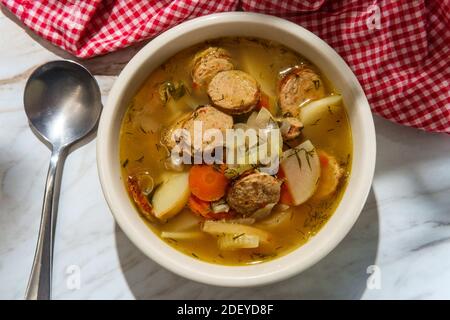 Gemüsehühnerwurst Nudelsuppe mit Hühnerbrühe auf Marmor Küchentisch Stockfoto