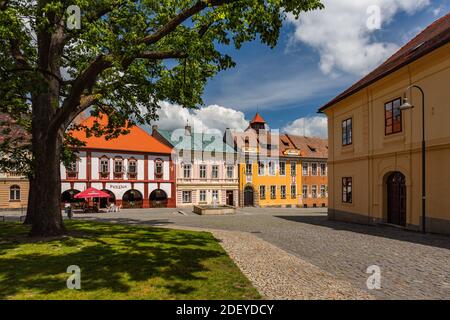 Opocno, Tschechische Republik - Juni 16 2020: Blick auf den Trckovo Platz mit Kopfsteinpflasterstraße, bunten Häusern, einem Brunnen, einem Baum und einer grünen Wiese. Stockfoto