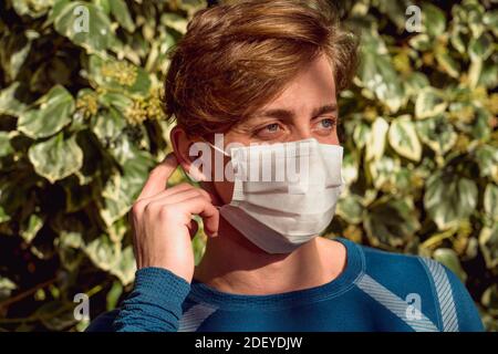 Porträt eines Mannes, der eine Schutzmaske vor einem mit Efeu bedeckten Hintergrund trägt. Stockfoto