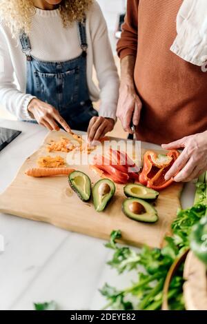 Stock Foto von einer Frau und einem Mann mittleren Alters, der Essen in einer Küche zubereitet. Sie hacken etwas Gemüse. Sie sind nicht erkennbar. Stockfoto