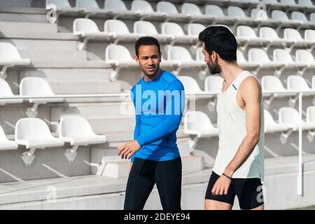 Stock Foto von zwei Freunden Athleten tragen Sportkleidung chatten und gehen in der Sportstrecke. Stockfoto