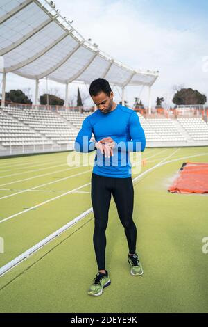 Stock Foto von afroamerikanischen Athleten mit Uhr, während auf der Laufstrecke stehen. Stockfoto