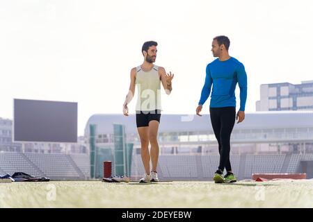 Stock Foto von zwei Freunden Athleten tragen Sportkleidung chatten und gehen in der Sportstrecke. Stockfoto