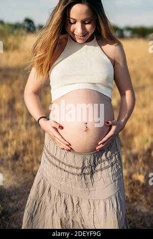 Stock Foto von schwangeren Frau berühren ihren Bauch und Blick auf die Landschaft. Stockfoto