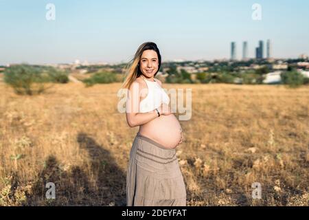 Stock Foto von schwangeren Frau berühren ihren Bauch und Blick auf die Kamera. Stockfoto