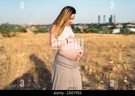 Stock Foto von schwangeren Frau berühren ihren Bauch und Blick auf die Landschaft. Stockfoto