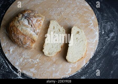 Traditionelle Weizenbrot Scheiben mit Mehl auf Holztisch.Konzept des Backens, Kochen isoliert auf schwarzem Hintergrund. Stockfoto