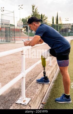 Behinderter Sportler, der während einer Pause sein Handy benutzt. Stockfoto