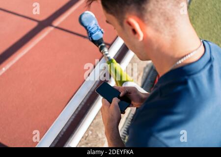 Behinderter Sportler, der sein Telefon im Stadion benutzt. Stockfoto