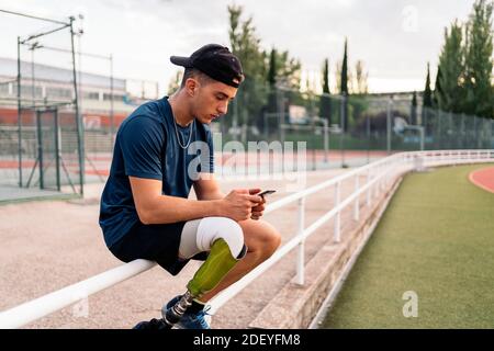 Behinderter Sportler, der während einer Pause sein Handy benutzt. Stockfoto