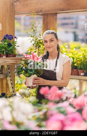 Stock Foto von schönen mittleren Alter Frau in Pflanzenkindergarten lächelnd und Blick auf die Kamera. Stockfoto