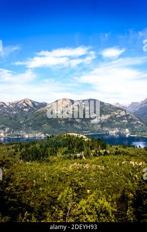 Schöne Landschaft von einem Hügel in Bariloche, Argentinien an einem sonnigen Sommertag. Berge, Seen, Pinien und blauer Himmel. Stockfoto