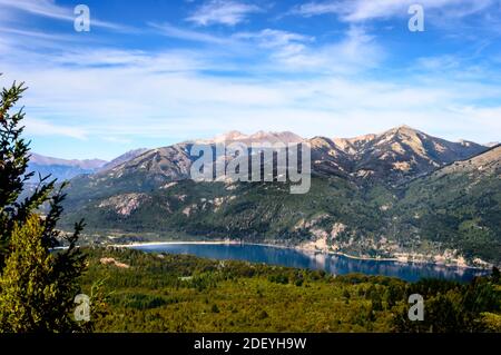 Schöne Landschaft von einem Hügel in Bariloche, Argentinien an einem sonnigen Sommertag. Berge, Seen, Pinien und blauer Himmel. Stockfoto