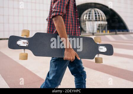 Stock Foto von unerkannten Skater Jungen zu Fuß in der Stadt mit seinem Longboard. Stockfoto