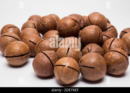 Ganze Macadamianüsse auf weißem Hintergrund. Gesunder vegetarischer Snack. Nahaufnahme. Copy-Space für Ihren Text. Stockfoto