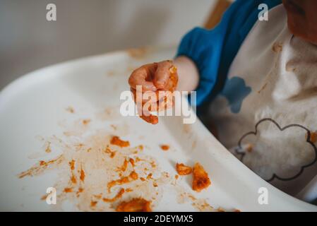 Nahaufnahme der Hände eines Babys beim Essen und Making Ein Chaos Stockfoto