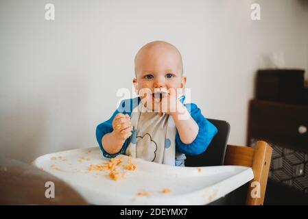 Liebenswert Baby lernen, wie man essen machen einen Mess Finger Im Mund Stockfoto