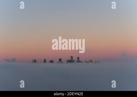 Stadt in den Wolken, Paradise City, City of Angels, Vancouver City Wolkenkratzer über dem Nebel mit der Morgensonne, die einen reflektierenden falschen Sonnenuntergang erzeugen Stockfoto