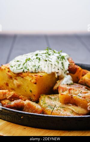 Nahaufnahme von Kartoffelauflauf mit gebratenem Schweinefleisch Mini Bauchscheiben auf dunklem Holztisch Stockfoto