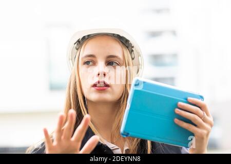 Junge Ingenieurin weiblich mit Tablet und Arbeitshelm draußen Stockfoto