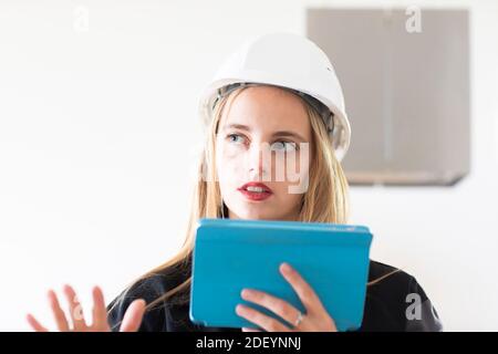 Junge Ingenieurin weiblich mit Tablet und Arbeitshelm innen Stockfoto