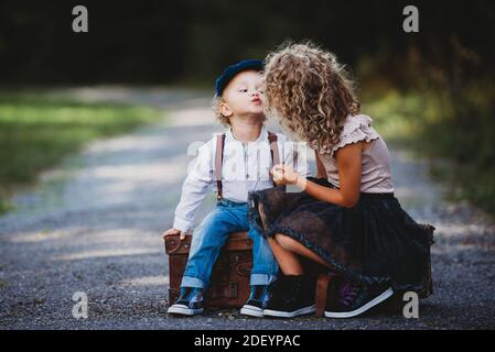 Entzückende Kinder sitzen auf einem Vintage-Koffer werfen einen Kuss Stockfoto