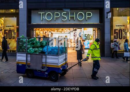 London, Großbritannien. Dezember 2020. Sammeln des Mülls außerhalb Struggling Top Shop bietet 50% Rabatte in der Hoffnung, dass seine Mutter, Arcadia, überleben kann - Käufer sind in Kraft, in der Hoffnung, abholen ein vorweihnachtliches Schnäppchen, am ersten Tag sind die Geschäfte für mehrere Wochen geöffnet. Aber dies sind immer noch schwierige Zeiten für Einzelhändler, wie sie versuchen, aufzuholen, nachdem die zweite Coronavirus Lockdown endet. Kredit: Guy Bell/Alamy Live Nachrichten Stockfoto